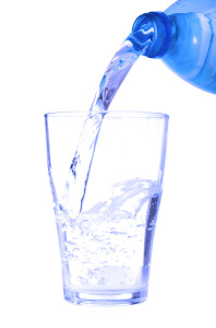 plastic bottle pouring fresh water on a glass (isolated on white background)